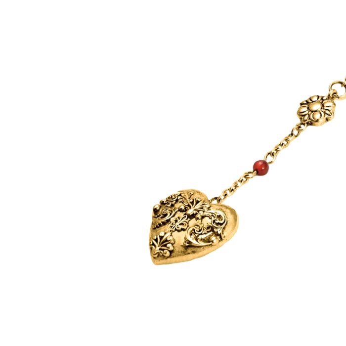 Close-up of a gold heart pendant with ornate filigree texture and engraved finish