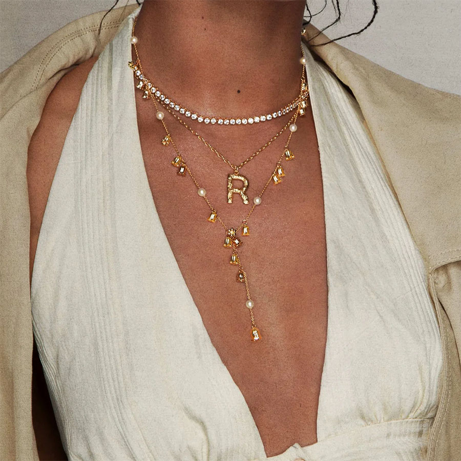 Gold lariat necklace flat lay with lily charms and pearl accents