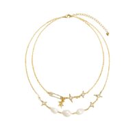 Gold layered charm necklace with adjustable extender and safety pin charm, close-up on white