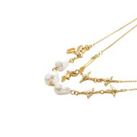 Layered gold necklace with baroque pearl charms and glittering star details, product photo