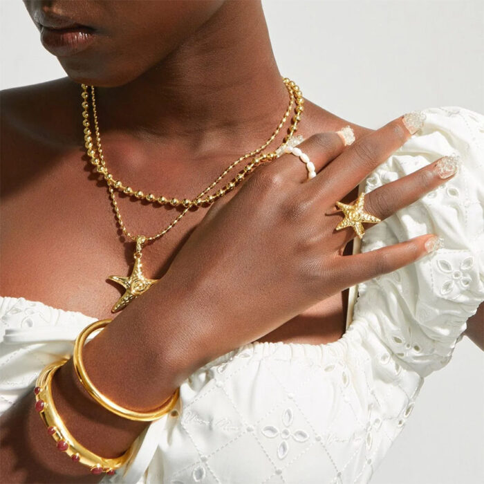 Gold Starfish Ring styled on model with gold jewelry stack, coastal fashion look