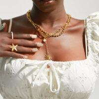 Gold Starfish Ring worn on hand with layered gold necklaces and white eyelet top