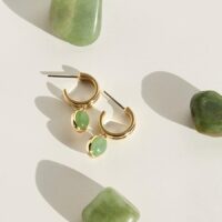Close-up on ear showing solitaire-style green stone charm hoop earrings