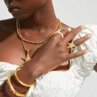 Model wearing a layered Starfish Necklace & Ring Set with gold bangles for a coastal chic summer look