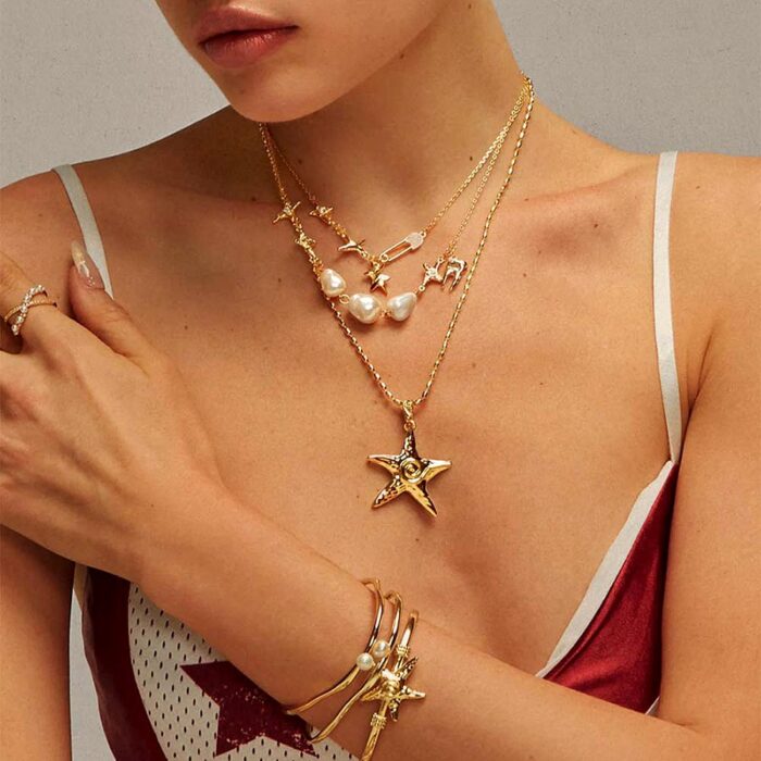 Starfish necklace in gold worn layered with pearl and charm necklaces