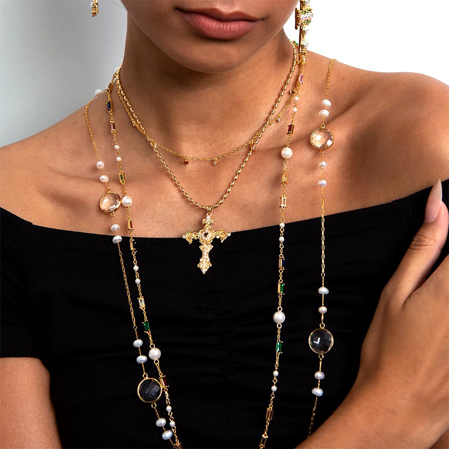 Aphrodite Cross Necklace styled with pearl strand necklace and gold chains for an old-money layered look.