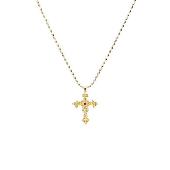 Gold-toned vintage filigree Aphrodite cross necklace with CZ stones and a red center gemstone on a white background.