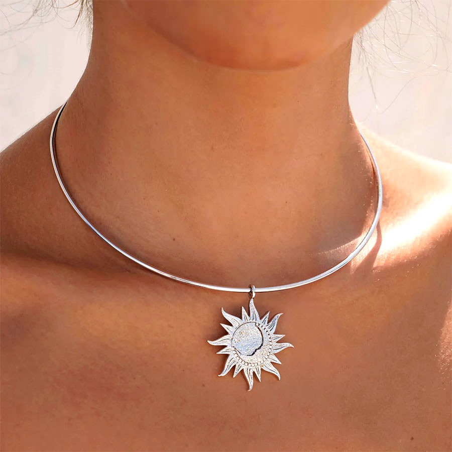Detail shot of Astra Choker Necklace showing a polished silver choker and sun pendant resting at the neckline, celestial choker styling