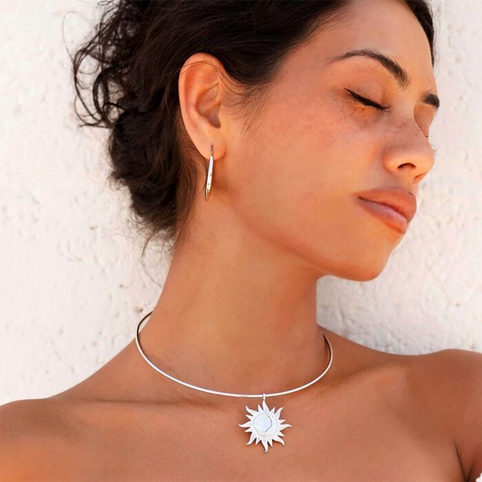 Astra Choker Necklace worn as a thin silver choker with a sun pendant, paired with matching silver hoop earrings in warm light