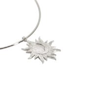 Minimalist celestial jewelry detail—Astra Choker Necklace sunburst charm with a crescent moon center in matte silver.