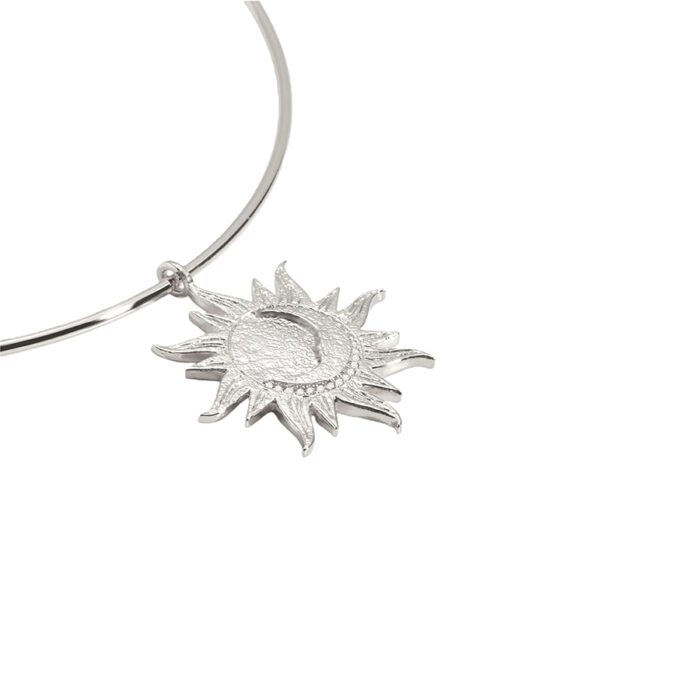 Minimalist celestial jewelry detail—Astra Choker Necklace sunburst charm with a crescent moon center in matte silver.