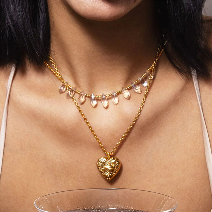 Belted Heart Charm Necklace worn on model with ornate gold heart locket pendant layered under crystal choker