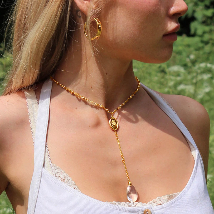 Dear Diary Necklace gold lariat worn with hoop earrings and a clear teardrop crystal pendant (outdoor close-up), casual chic look