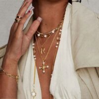Florence Cross Golden Necklace worn with a pearl choker and initial necklace for a coquette-inspired layered look