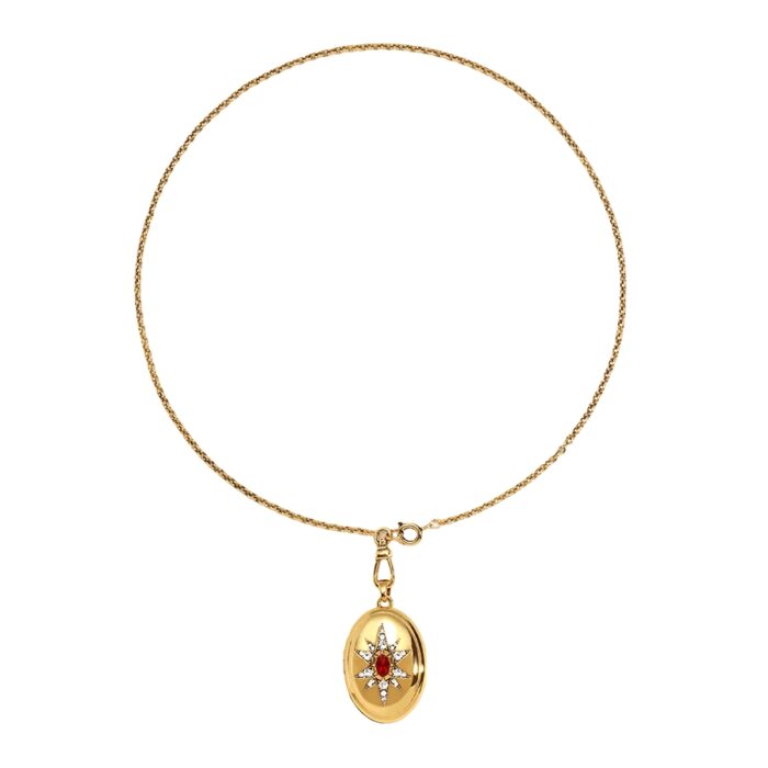 Gold locket necklace with textured chain and starburst pendant featuring red gemstone center