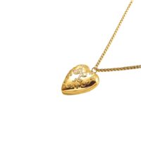 Vintage-style heart locket necklace with raised bow design and textured edges on a matching gold chain
