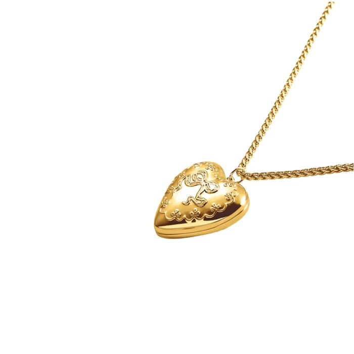 Vintage-style heart locket necklace with raised bow design and textured edges on a matching gold chain