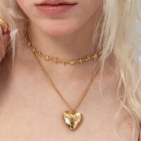 Heart locket necklace styling on model with layered gold necklaces, choker plus rope chain locket