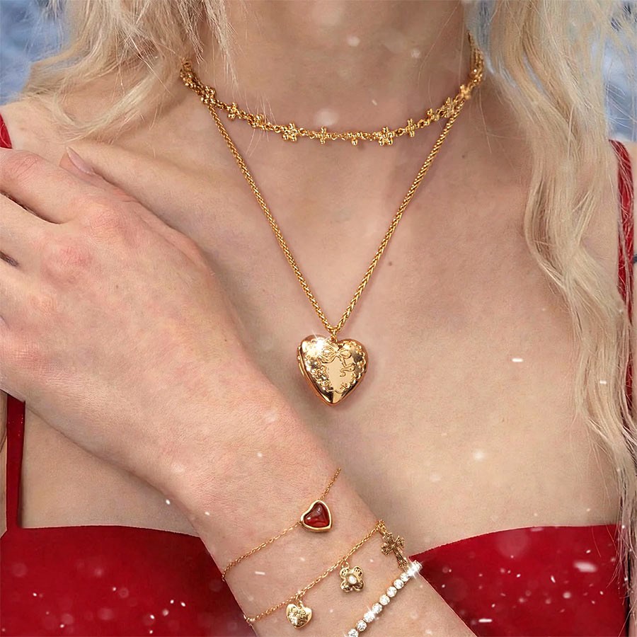 Lifestyle photo of a heart locket necklace paired with a floral-pattern choker and mixed gold bracelets