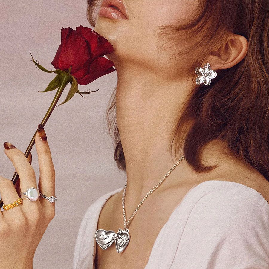 Model styling the Isabela Photo Locket Necklace with statement rings and a red rose, romantic gift aesthetic