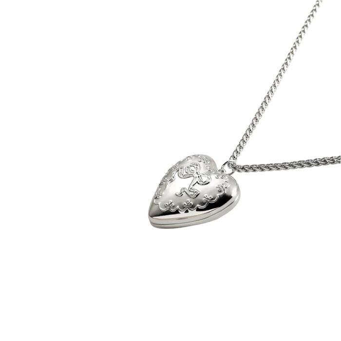 Silver-tone heart locket pendant necklace with ornate embossed bow detail, product photo on white background
