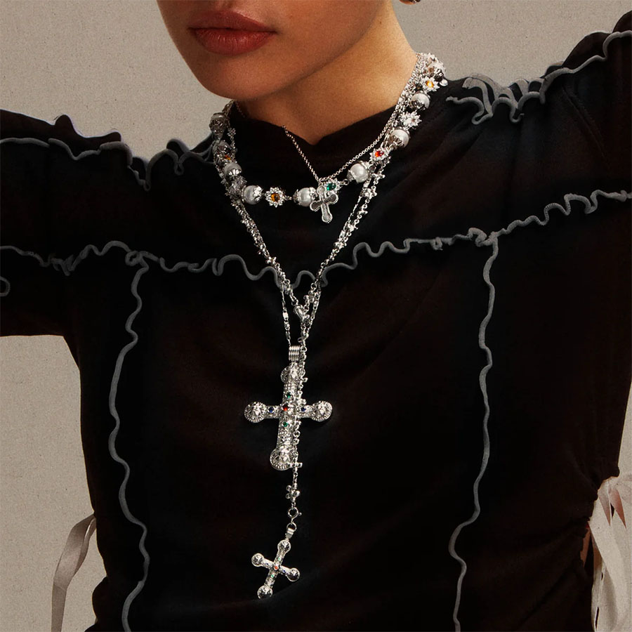 Model wearing pearl and gemstone y lariat necklace look with layered silver chains and cross pendants