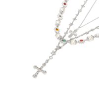 silver layered necklace set with mini cross pendant, pearl strand and multicolor gemstone beads, studio product photo